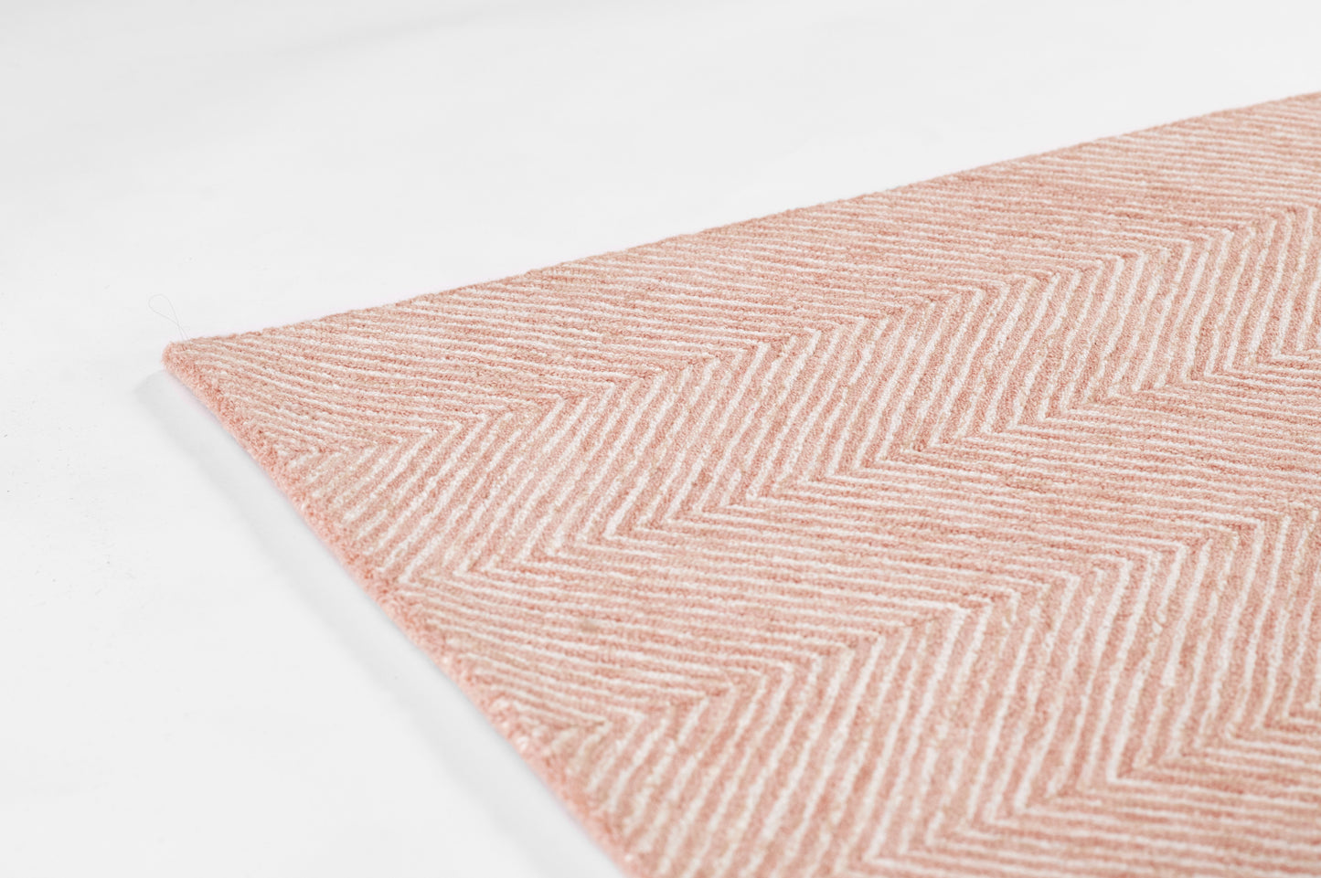 Soft pink herringbone plush rug with chevron pattern, corner view for cozy home decor.