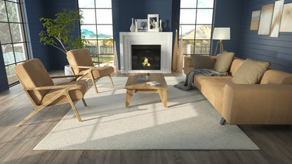 Taupe sofa and wooden armchairs around a wooden coffee table in a modern living room with fireplace and large windows.