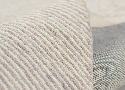 Taupe ribbed boucle fabric on a gray woven cushion, close-up of soft textured home decor.