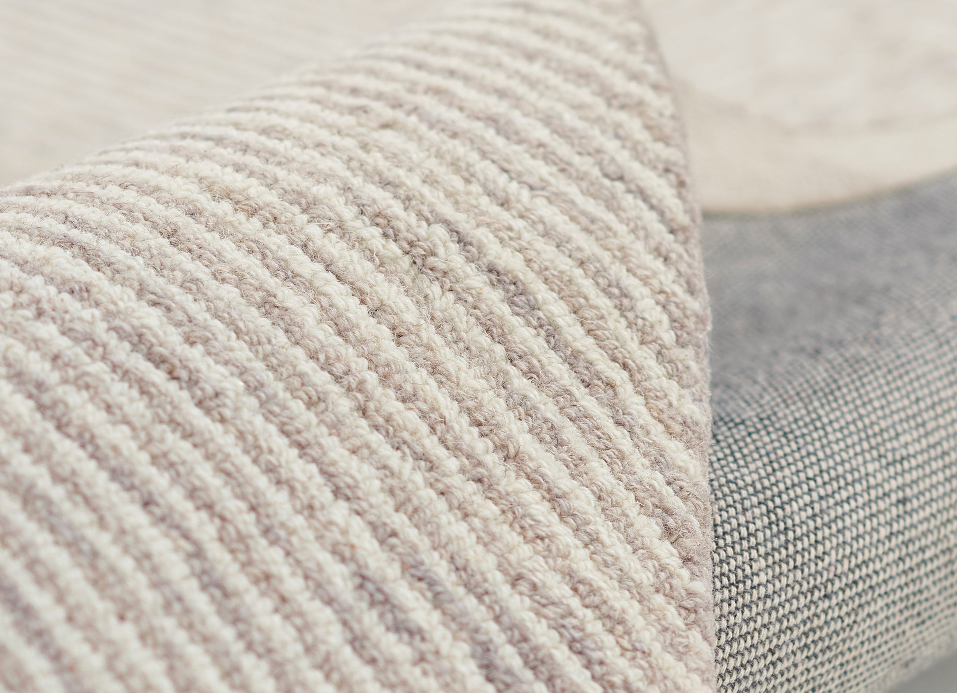 Taupe ribbed textured pillow on a gray woven cushion, cozy home decor accent.
