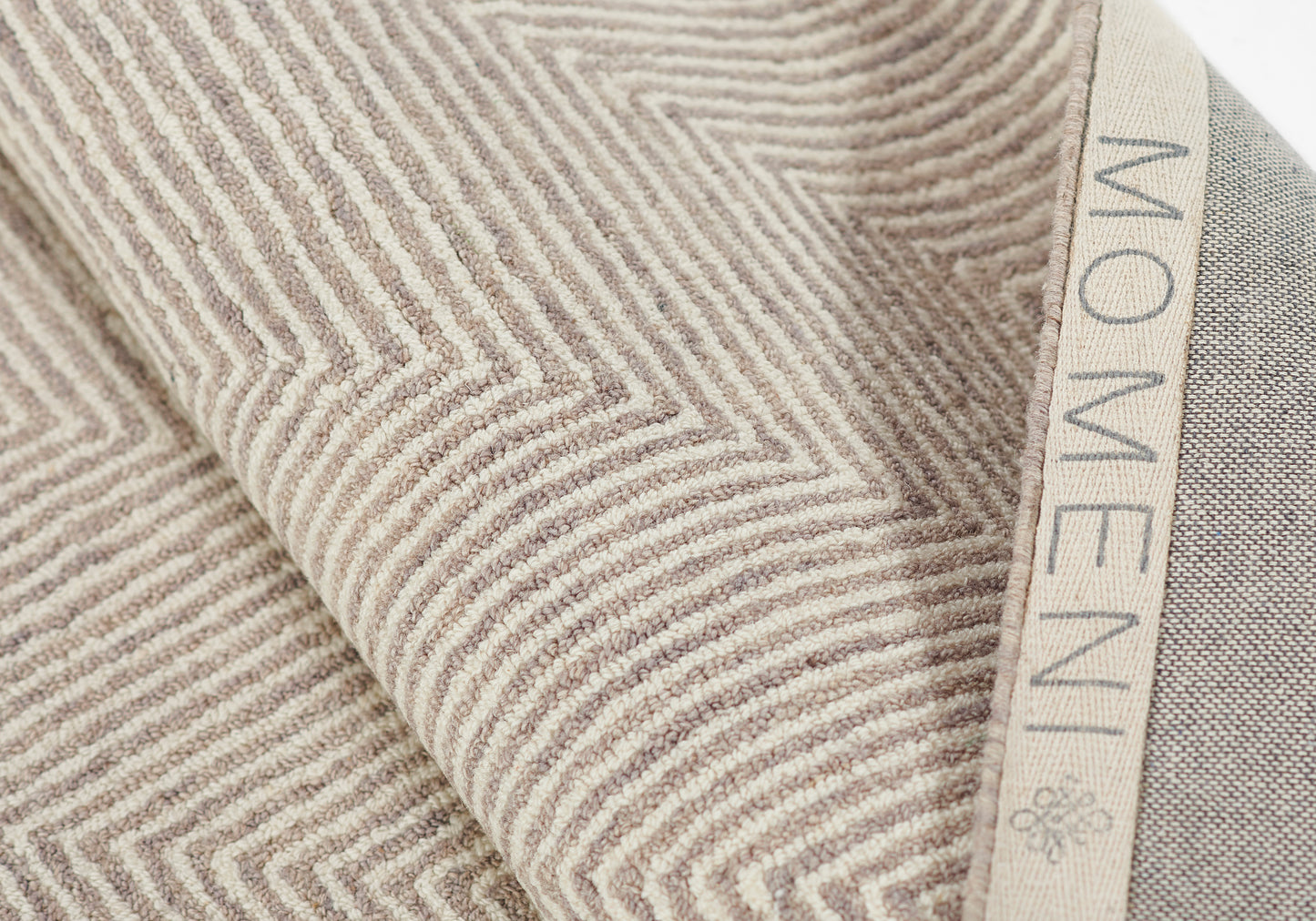 Taupe textured throw blanket with raised chevron pattern and beige woven border, soft and cozy.