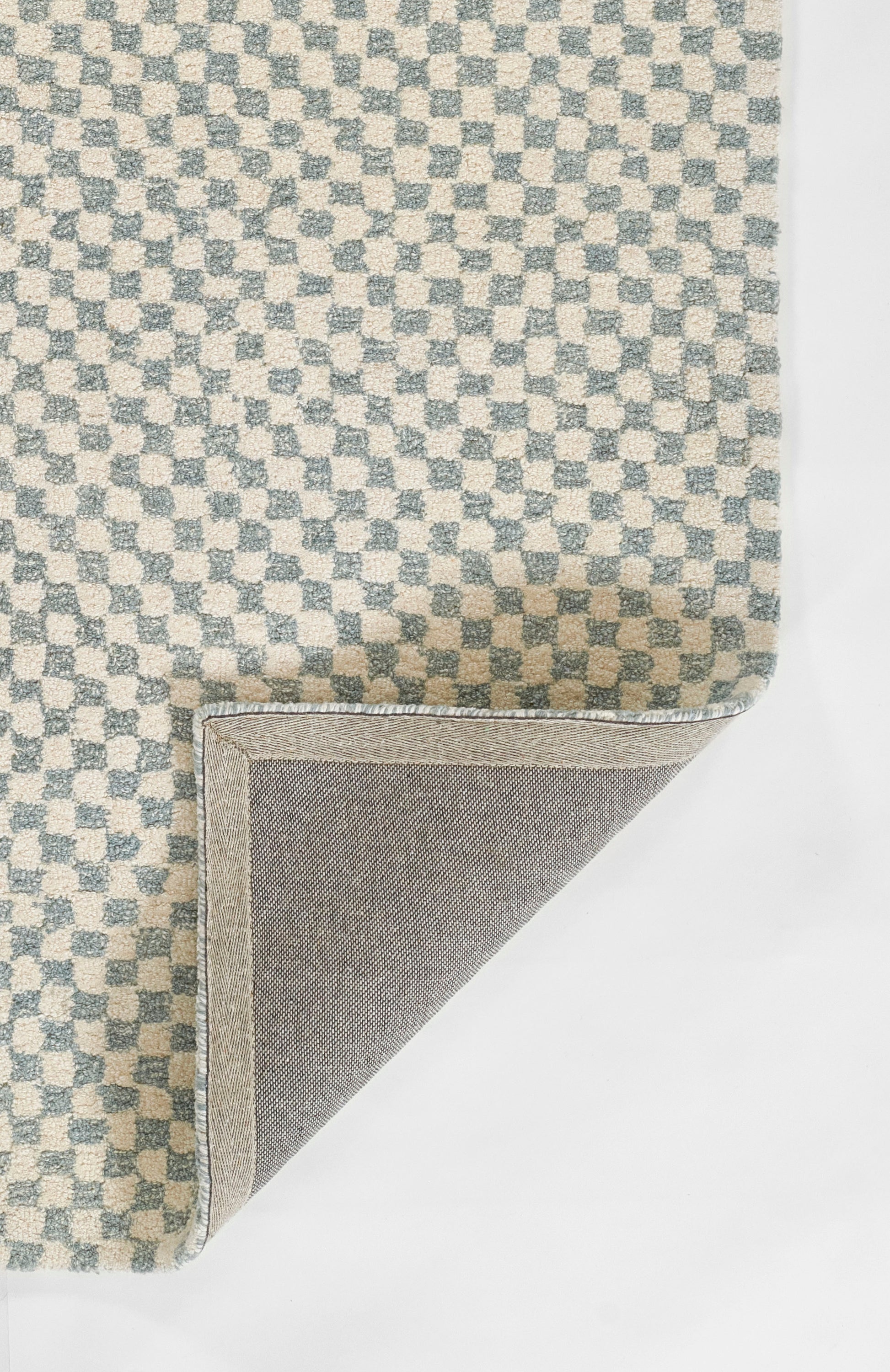 Blue and cream checkerboard woven rug with soft texture; folded corner reveals grey backing and pale blue binding.
