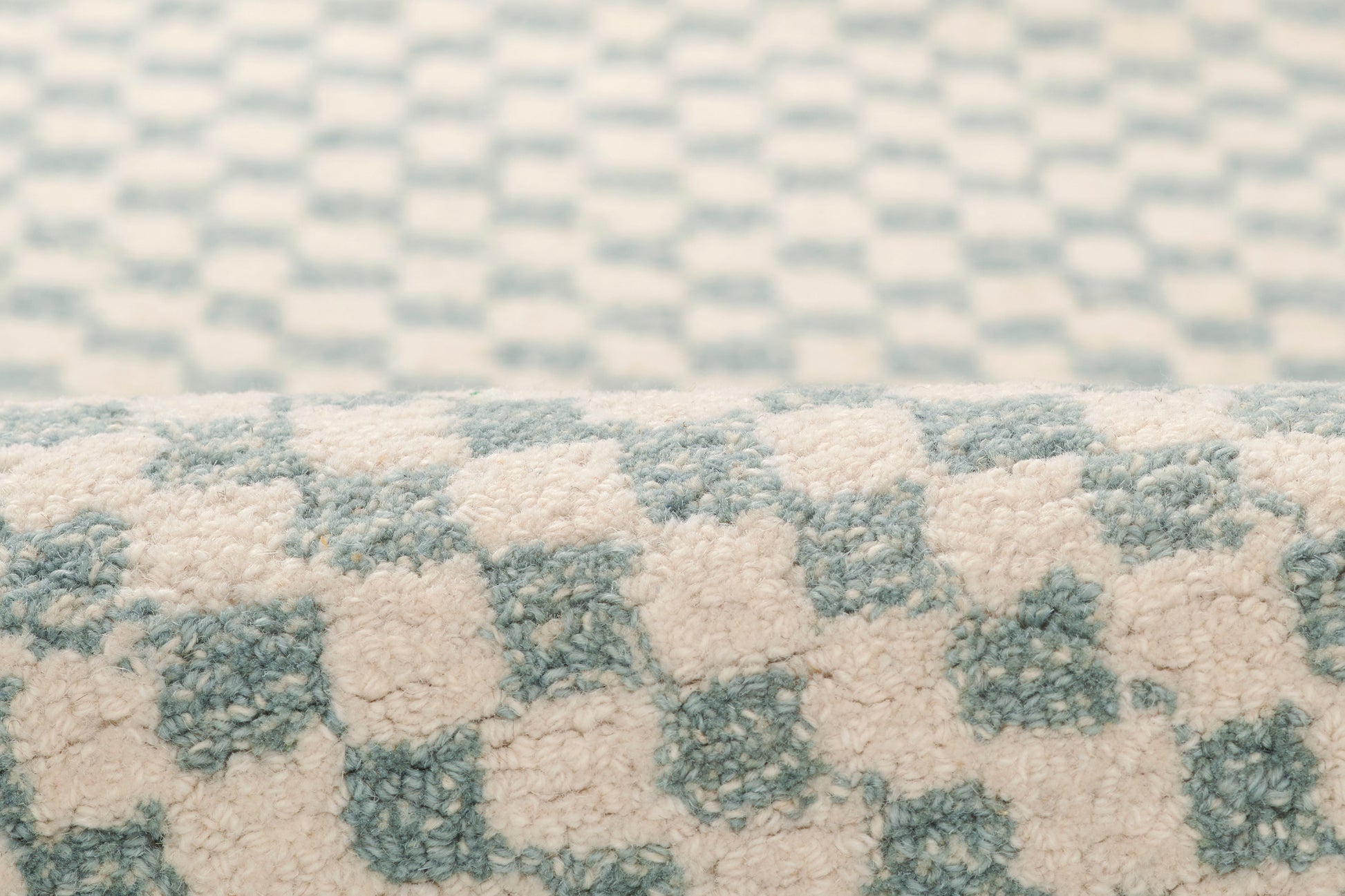 Macro view of a light blue and ivory checkerboard plush rug with soft, high-pile texture.