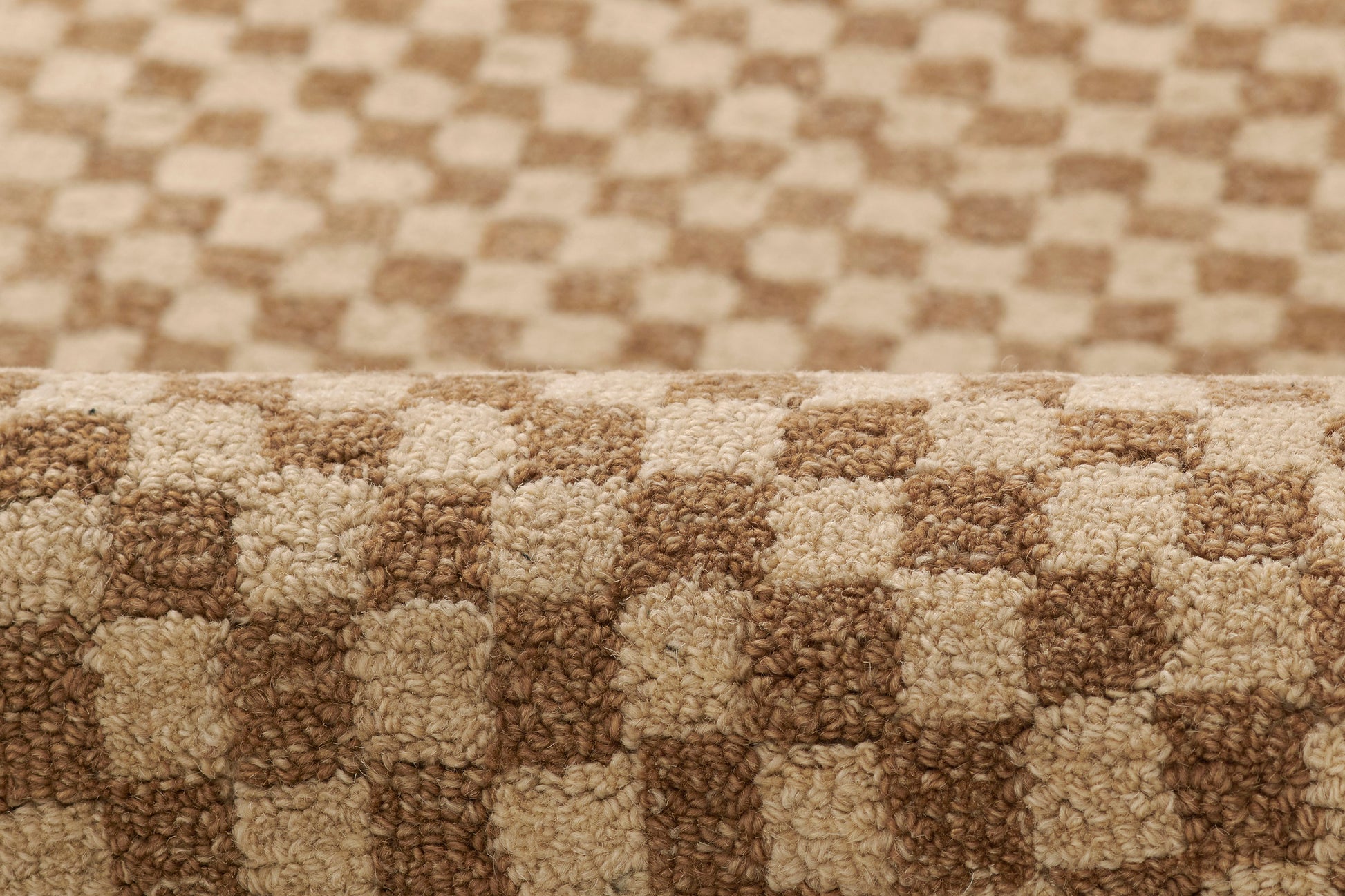 Beige and brown checkerboard shag rug with plush pile and rolled edge, ideal for living rooms.