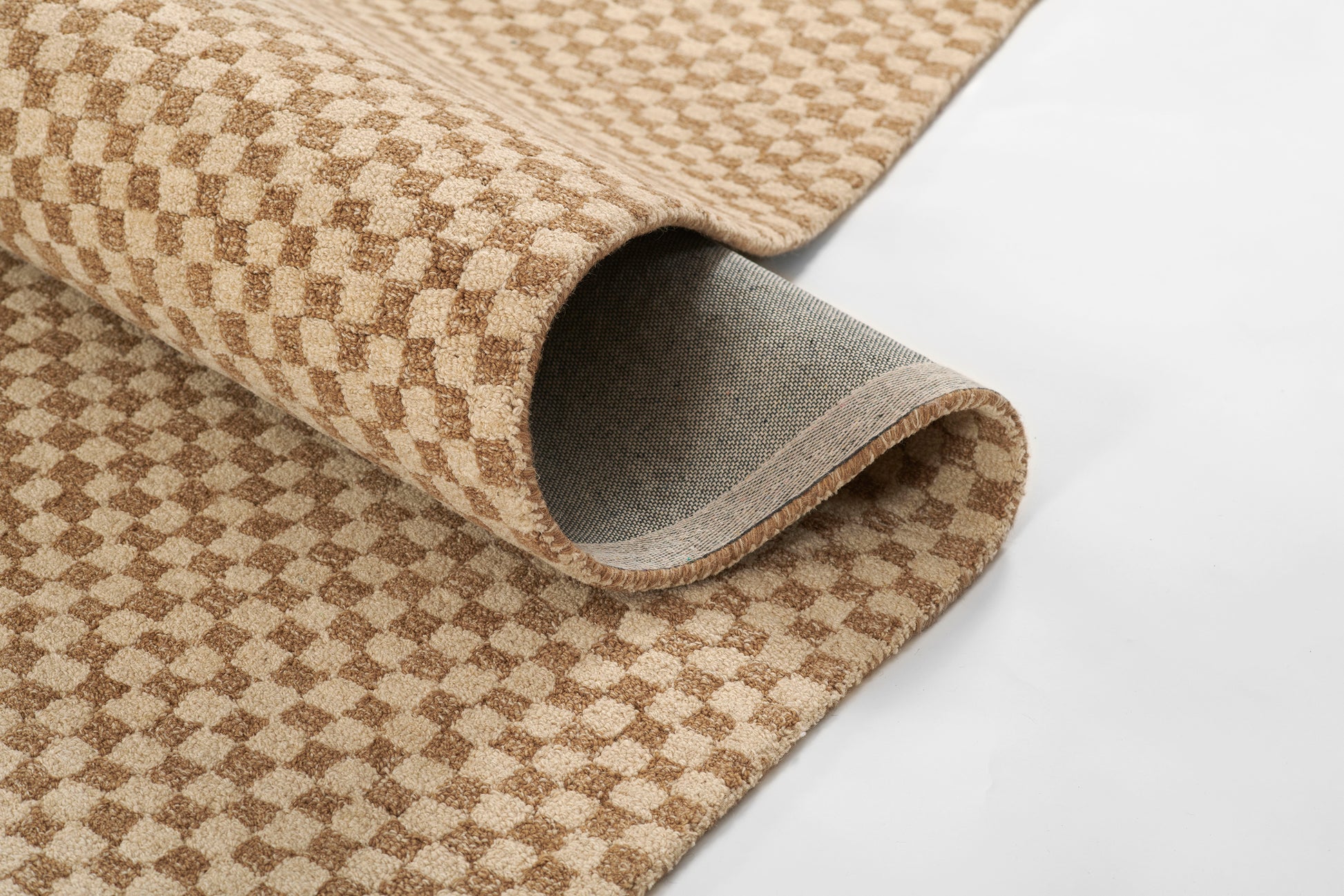 Beige and brown checkered rug rolled up, soft plush pile with bound edge and grey underside.