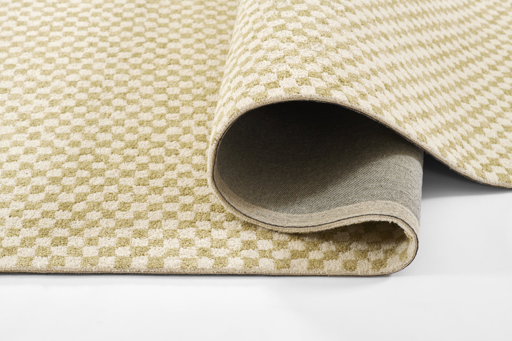 Beige and sage green checker rug in woven texture, rolled to show light grey backing; versatile home decor mat.