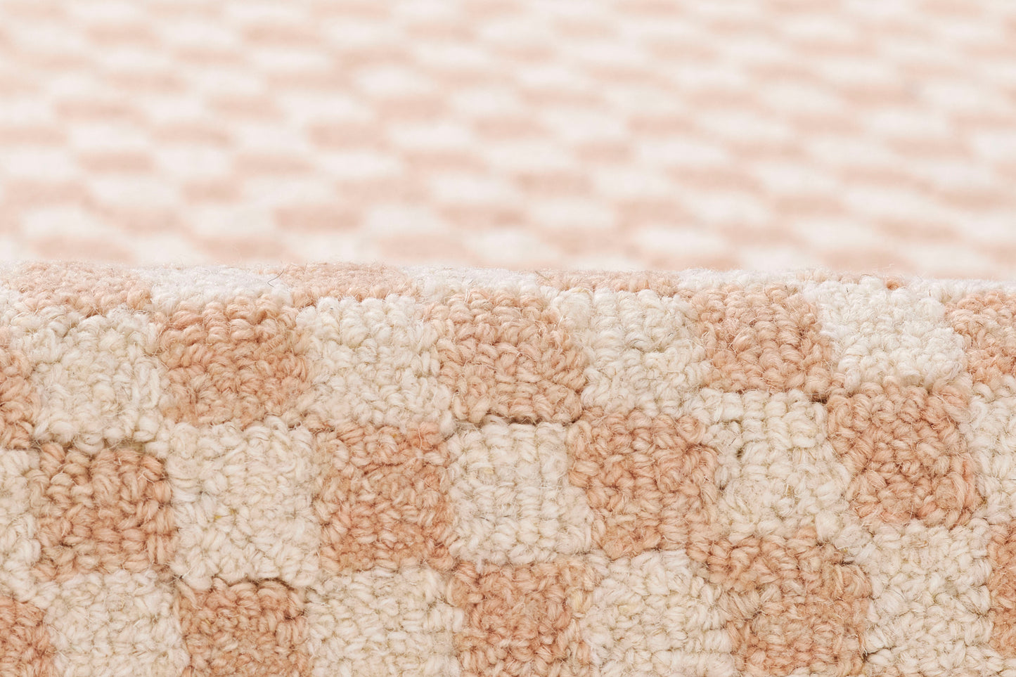 Peach and cream boucle rug with a plush loop pile in a checkerboard pattern for cozy living spaces.