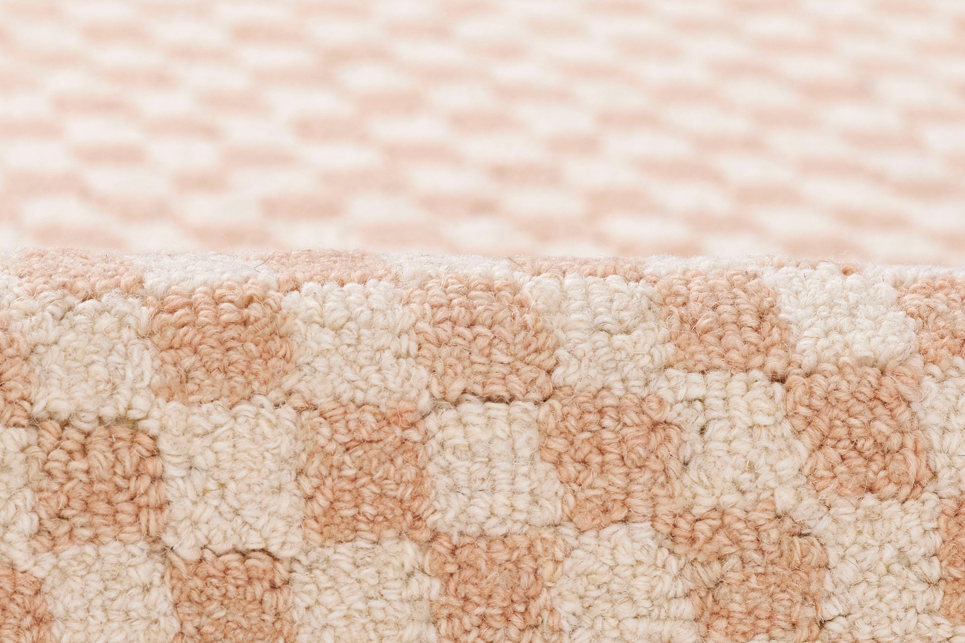 Peach and cream boucle rug with a plush loop pile in a checkerboard pattern for cozy living spaces.