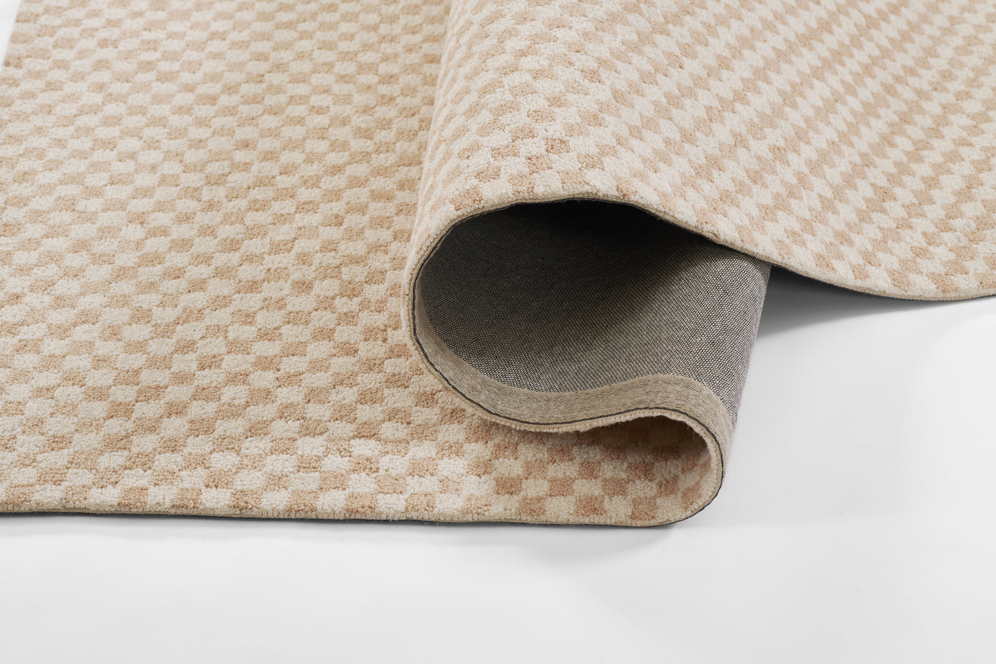 Beige and cream checkered rug with subtle diamond pattern, woven texture; rolled corner shows gray backing.