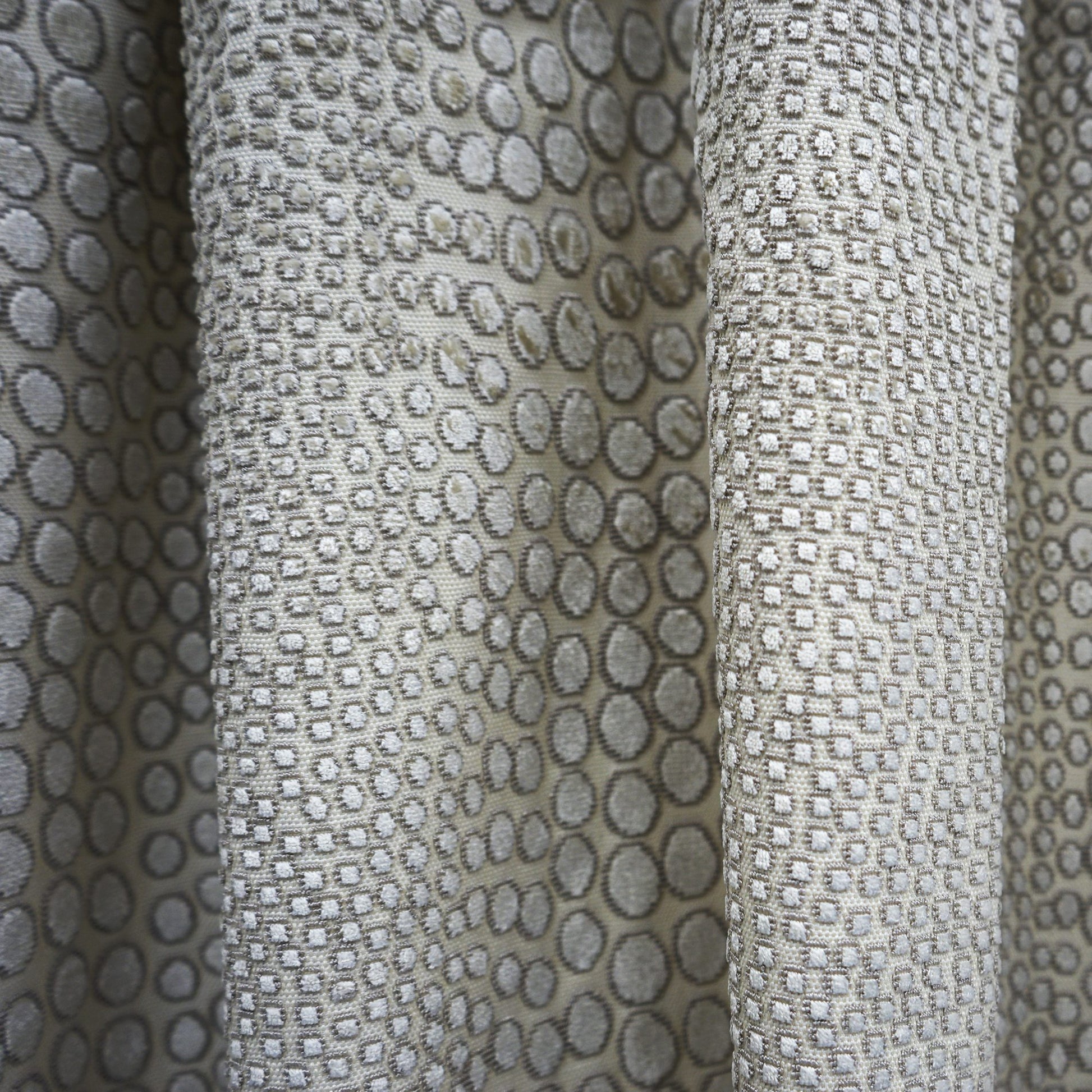 Beige cheetah-print curtain fabric with gray spots, textured velvet-like drapery material.