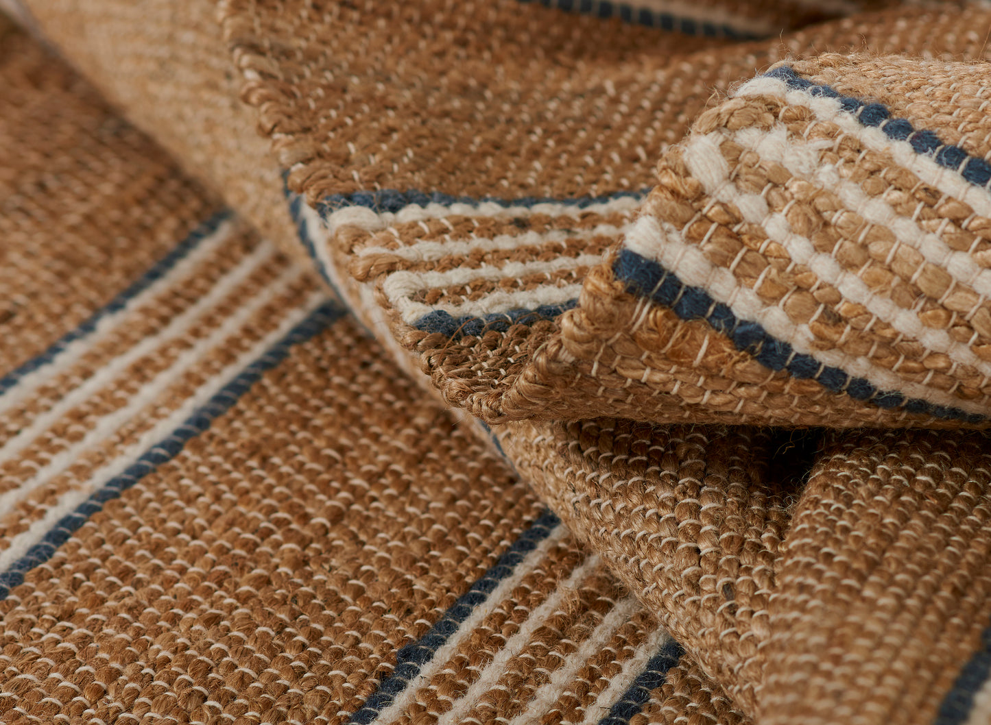 Natural jute rug with tan and cream stripes and blue accents; chunky woven texture.