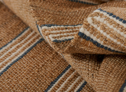 Natural jute rug with tan and cream stripes and blue accents; chunky woven texture.