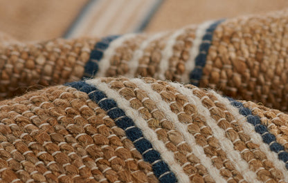 Close-up of natural jute rug with beige-brown fibers & navy blue stripes; rustic boho floor mat.