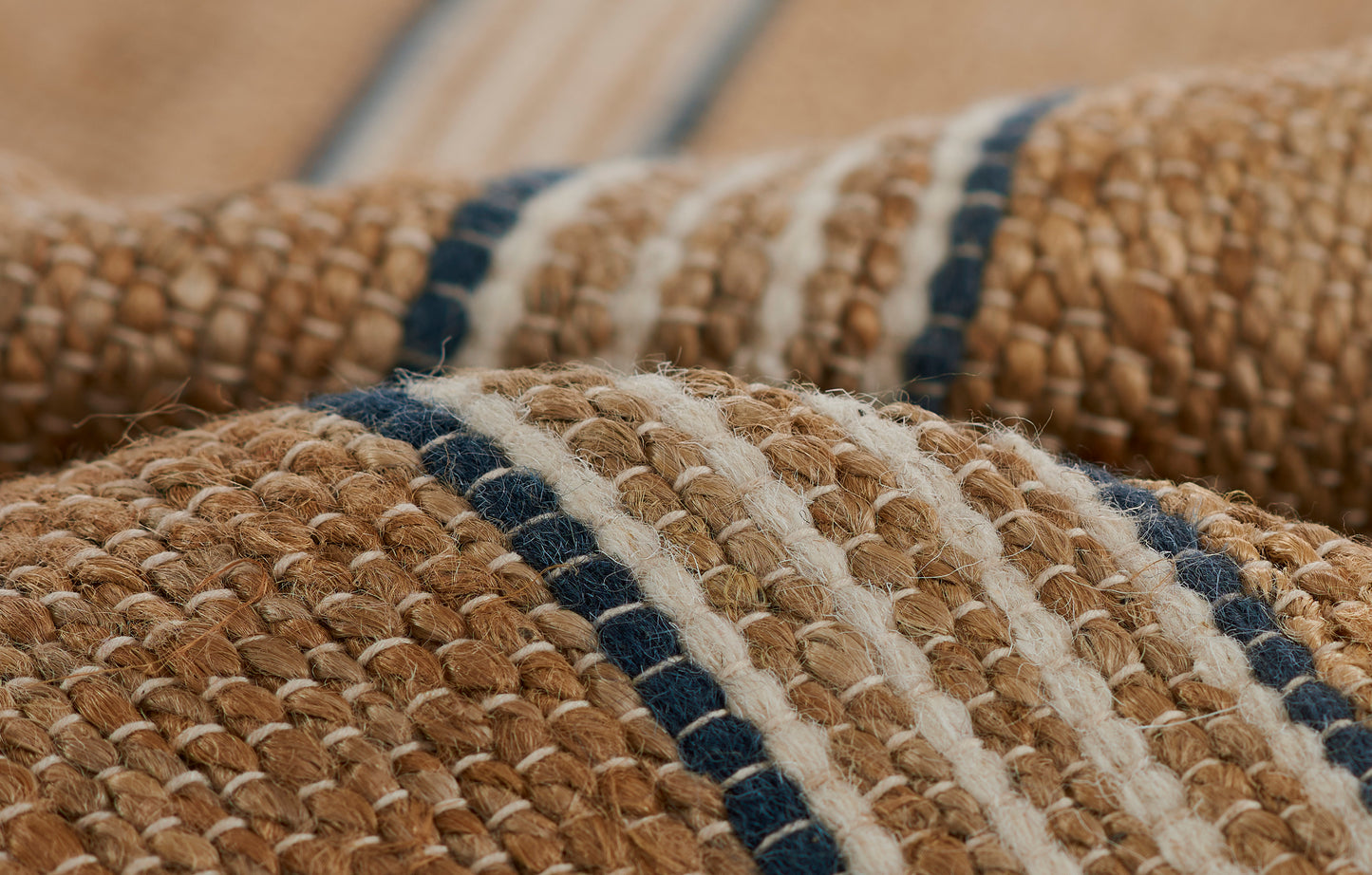 Natural jute rug with chunky weave in tan, cream and navy stripes; rustic coastal style.