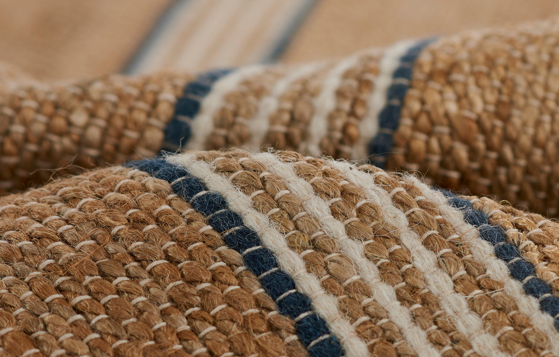 Natural jute rug with navy and cream stripes; chunky woven texture.