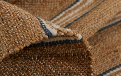 Natural brown handwoven jute rug with navy and white striped border, rolled edge.