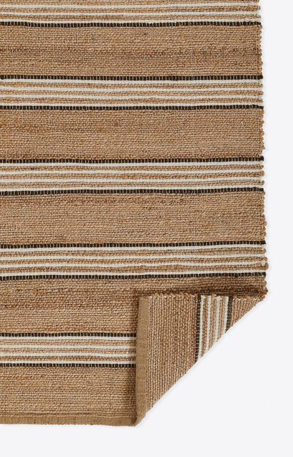 Natural jute rug with tan, beige and chestnut brown stripes; woven texture, folded corner.