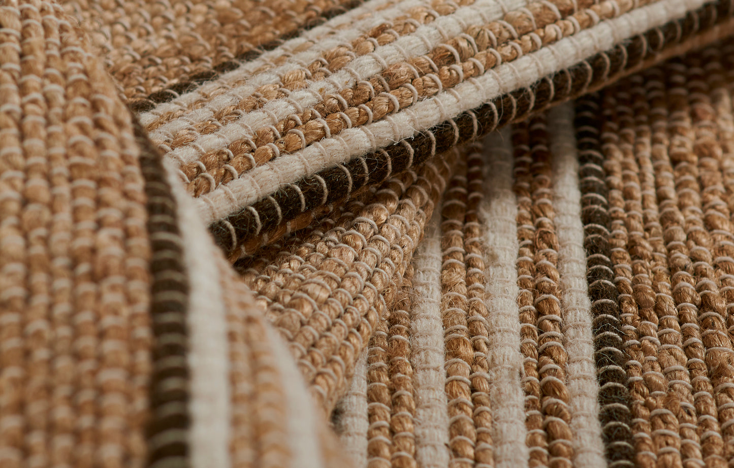 Close-up of a chunky jute rug with beige, tan and brown striped weave and looped fibers, 2' x 3'.