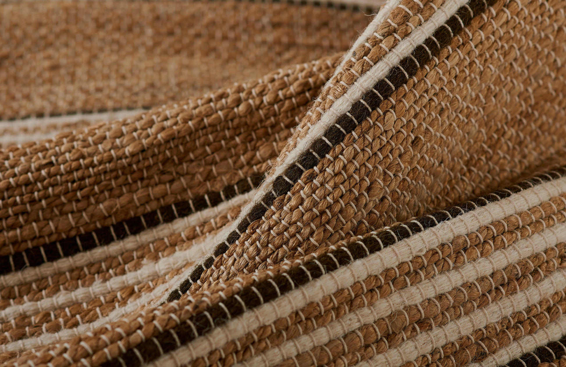 Close-up of a natural jute rug with brown and cream stripes and a chunky woven texture.
