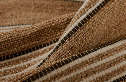 Close-up of a natural jute rug with brown and beige striped weave, rustic textured floor decor.