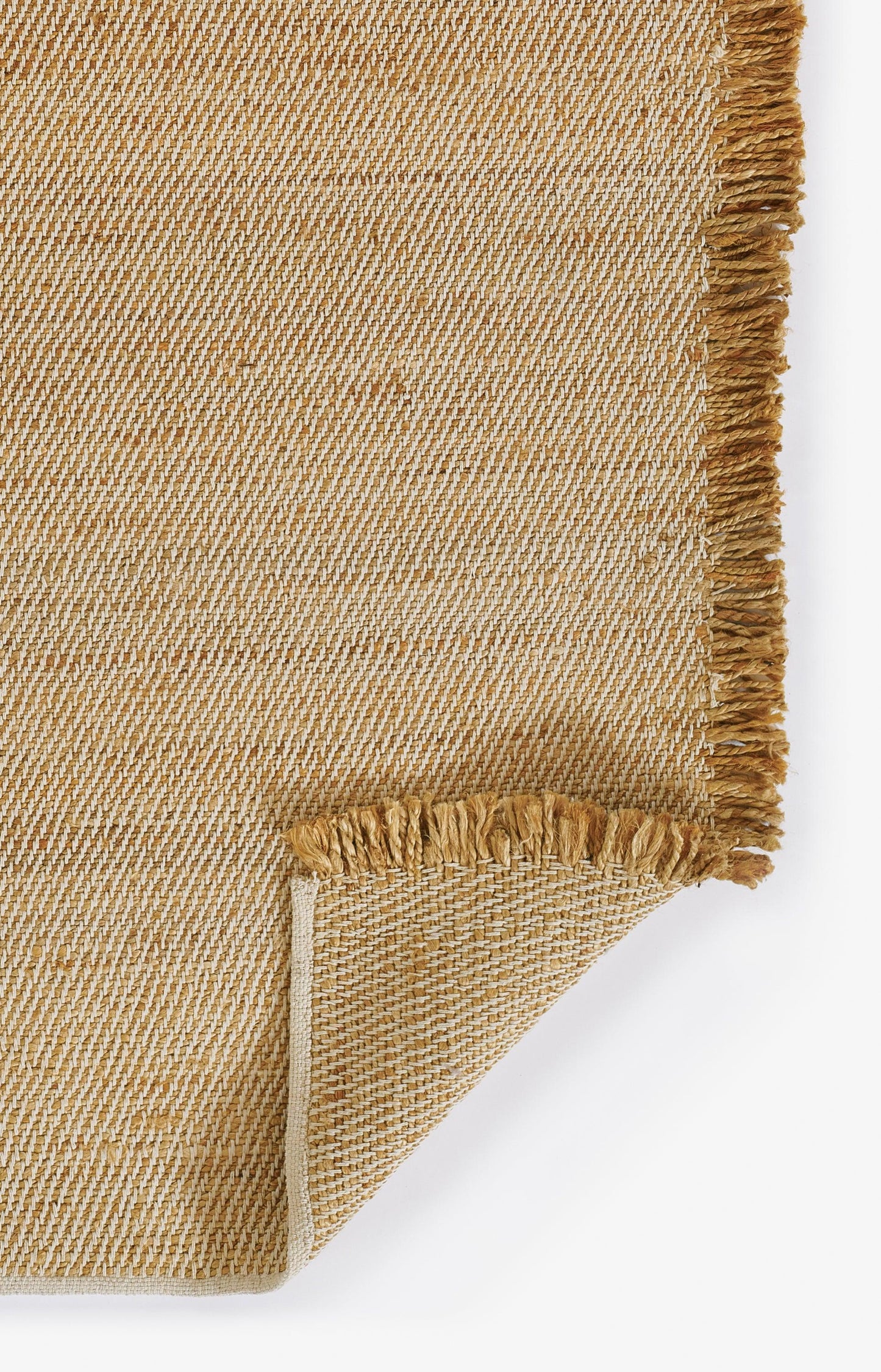 Natural jute rug in beige with fringe trim; diagonal textured weave, folded corner.