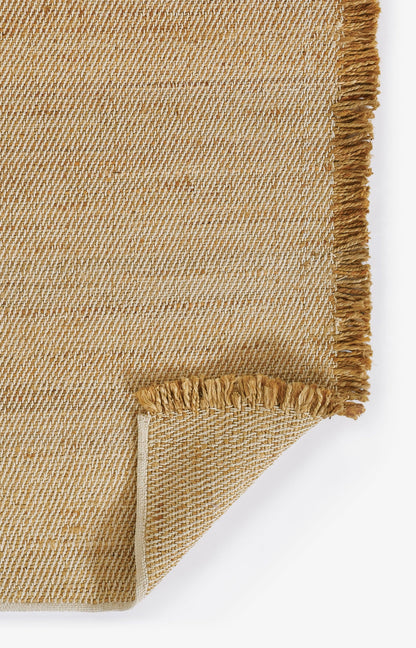 Natural jute rug in beige with fringe trim; diagonal textured weave, folded corner.