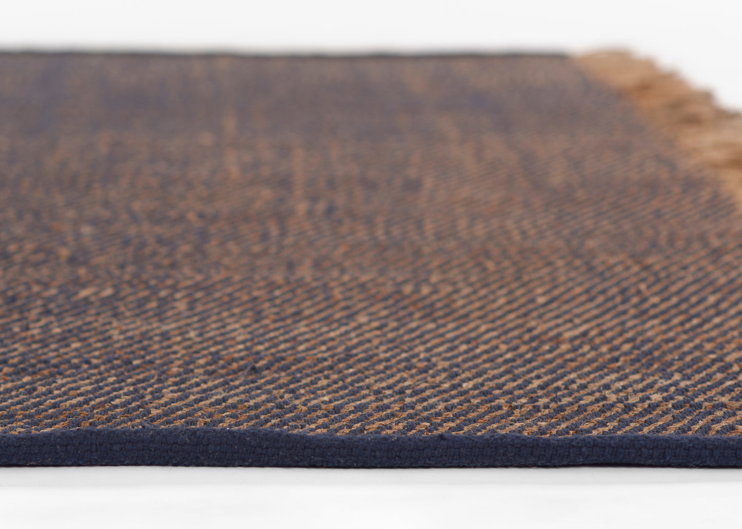 Close-up of a blue & brown woven rug with textured stripes and a dark navy border.