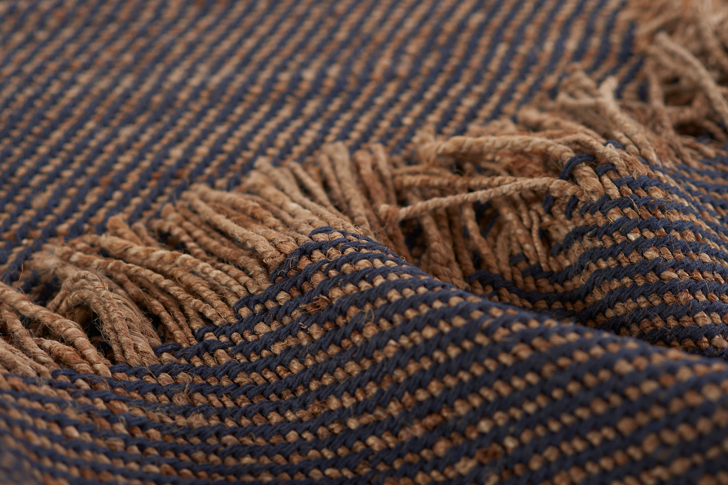 Blue and brown striped woven rug with fringe.