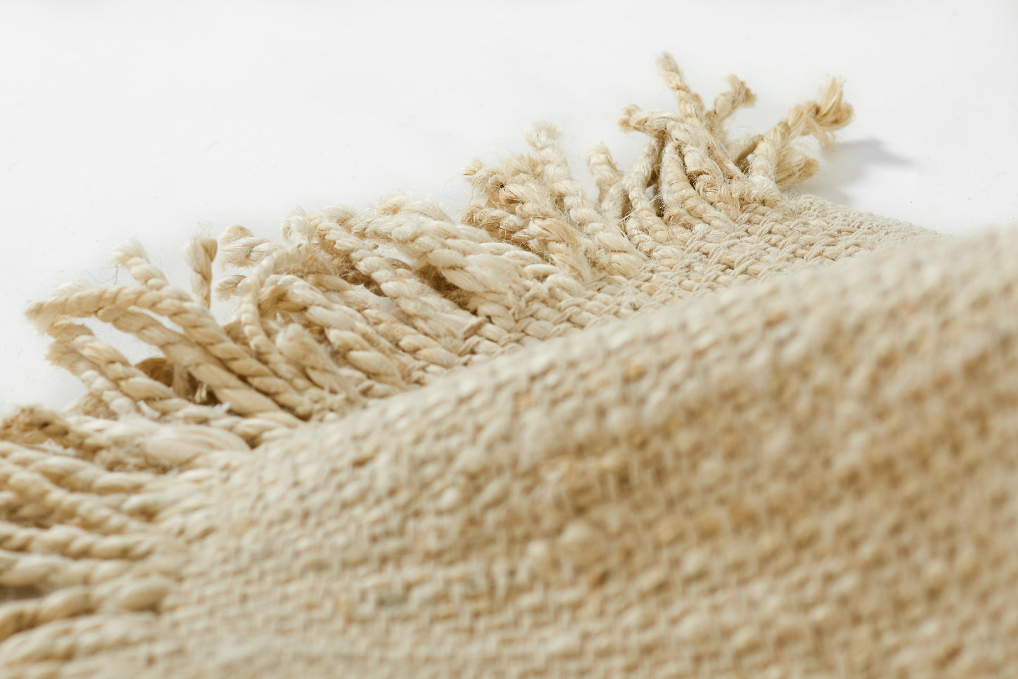 Natural beige woven rug with chunky fringe tassels and textured jute weave.