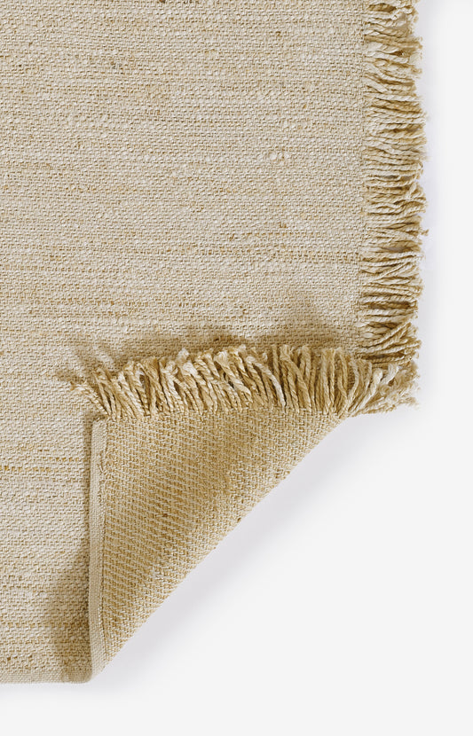 Natural beige woven rug with fringed edge and coarse jute texture.
