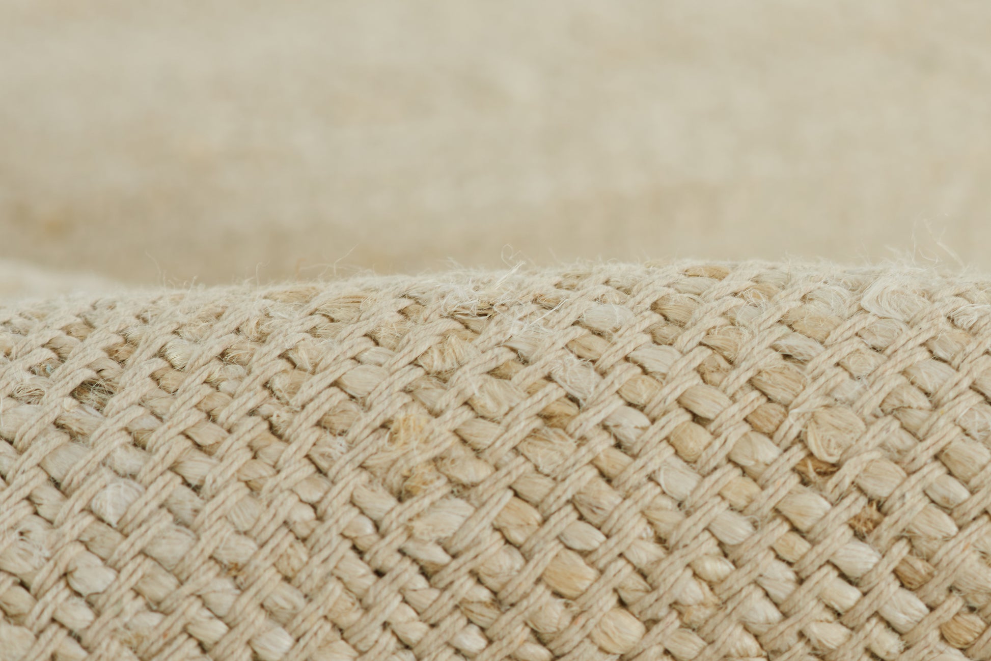 Natural beige straw-weave close-up on a rug, showing a braided texture.