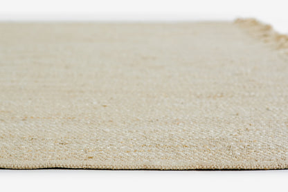 Natural beige woven jute rug with a textured surface and short fringe along one edge.