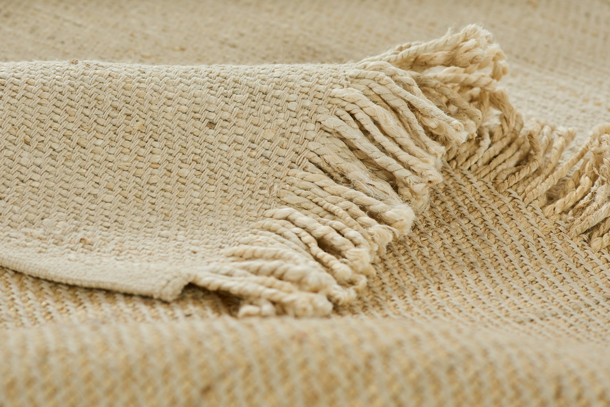 Beige woven jute rug runner with a fringed edge; rustic textured accent for cozy home decor.