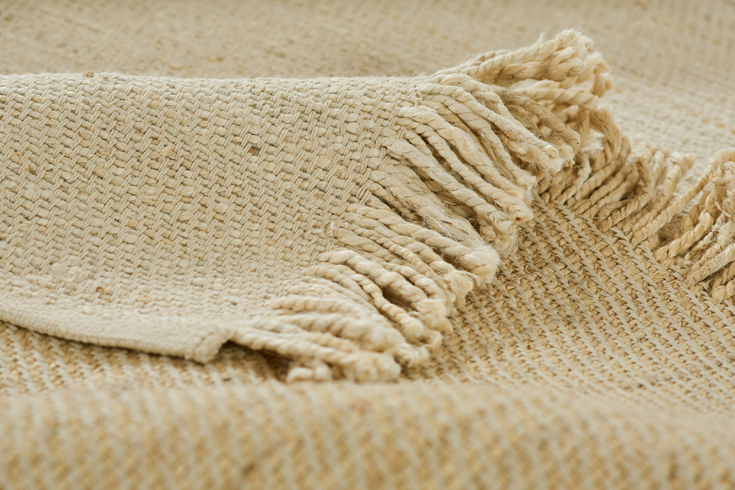 Beige woven jute-style rug with fringed edges and textured weave.