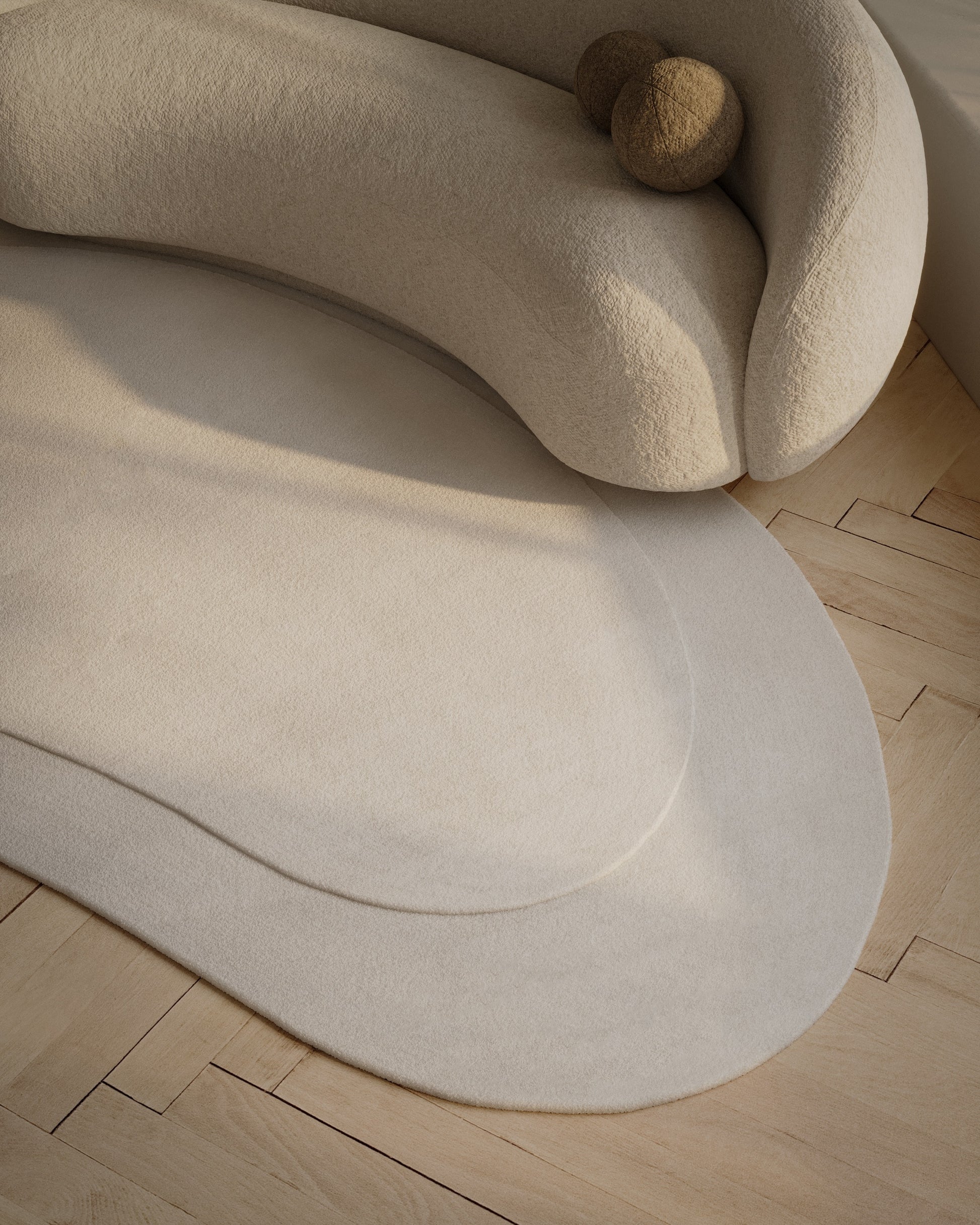 Cream boucle sofa with rounded arms and wooden ball accents, on light wood flooring with a matching oval rug.