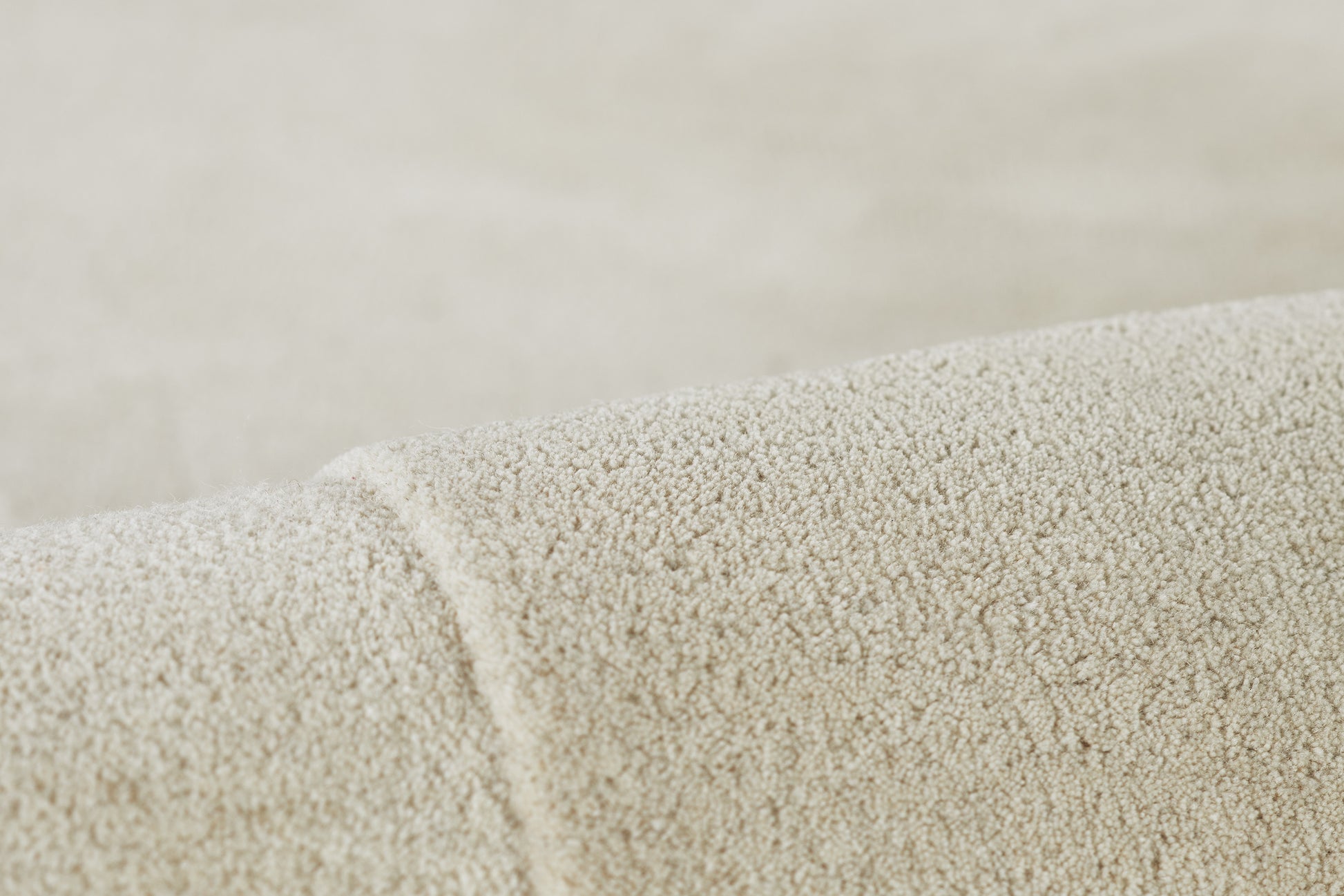Cream boucle rug close-up showing soft loop pile and rolled edge.