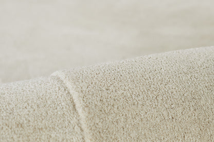 Cream boucle rug close-up showing soft loop pile and rolled edge.