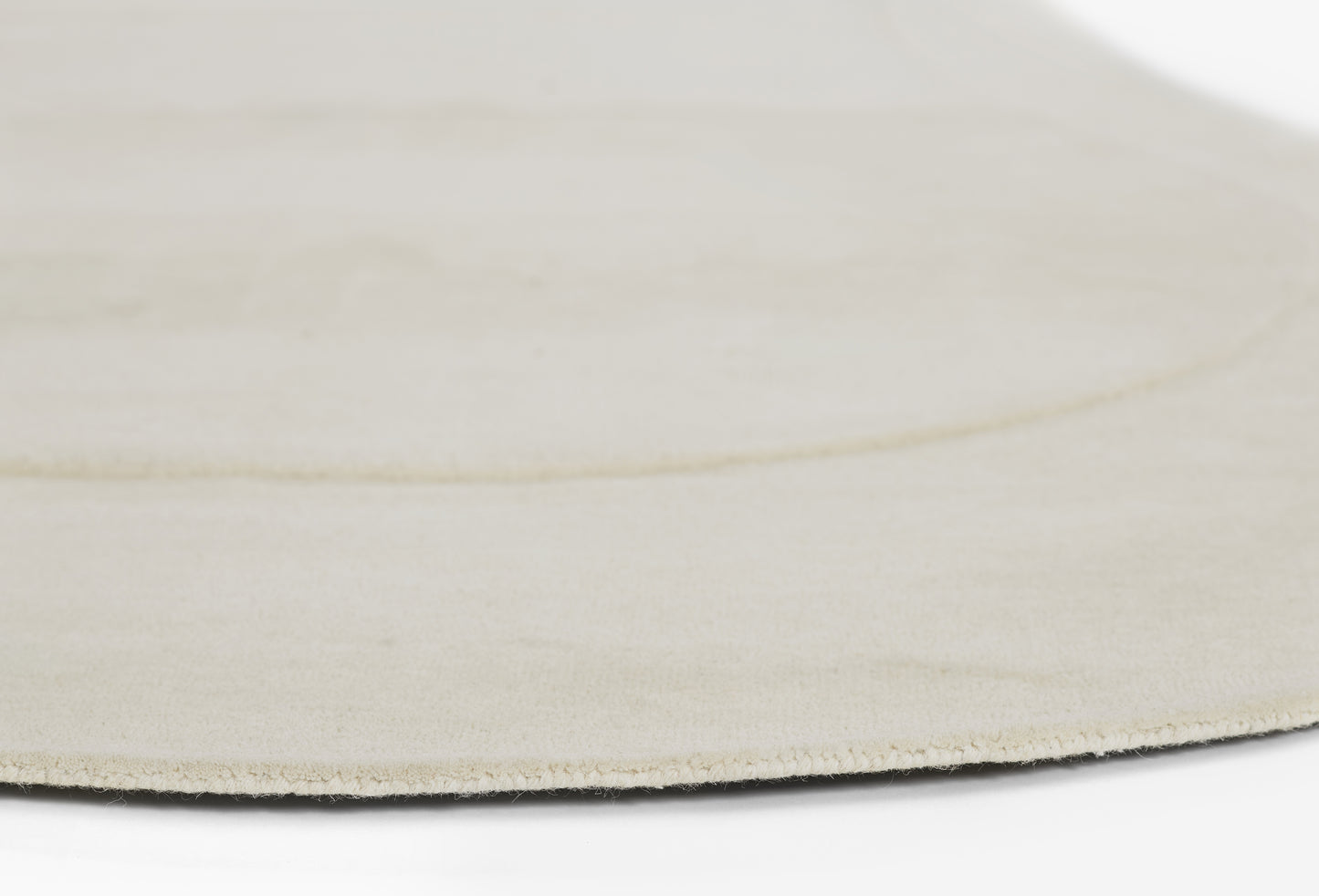 Cream round rug with soft, velvety texture and clean edge.