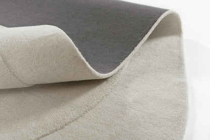 Two-tone felt rug with dark gray top and light beige underside, folded to show soft texture.