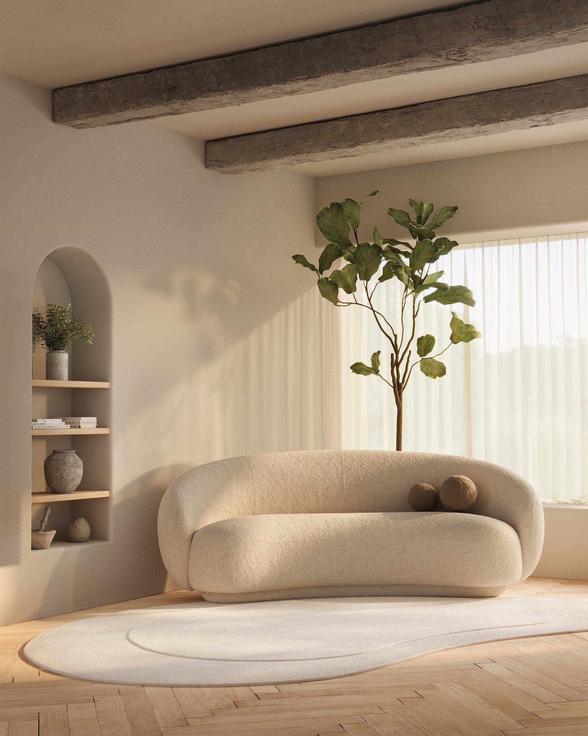 Round ivory boucle sofa in a bright living room with wooden beams, a tall fiddle-leaf fig, curved bookshelf niche & cream rug
