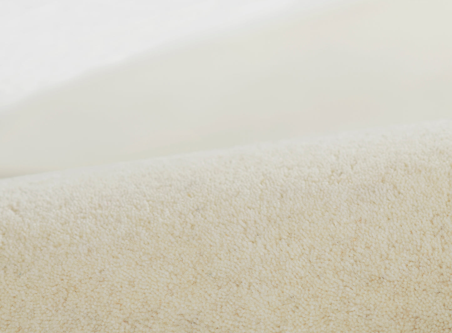 Close-up of a fine beige woven rug texture in pale cream tones.