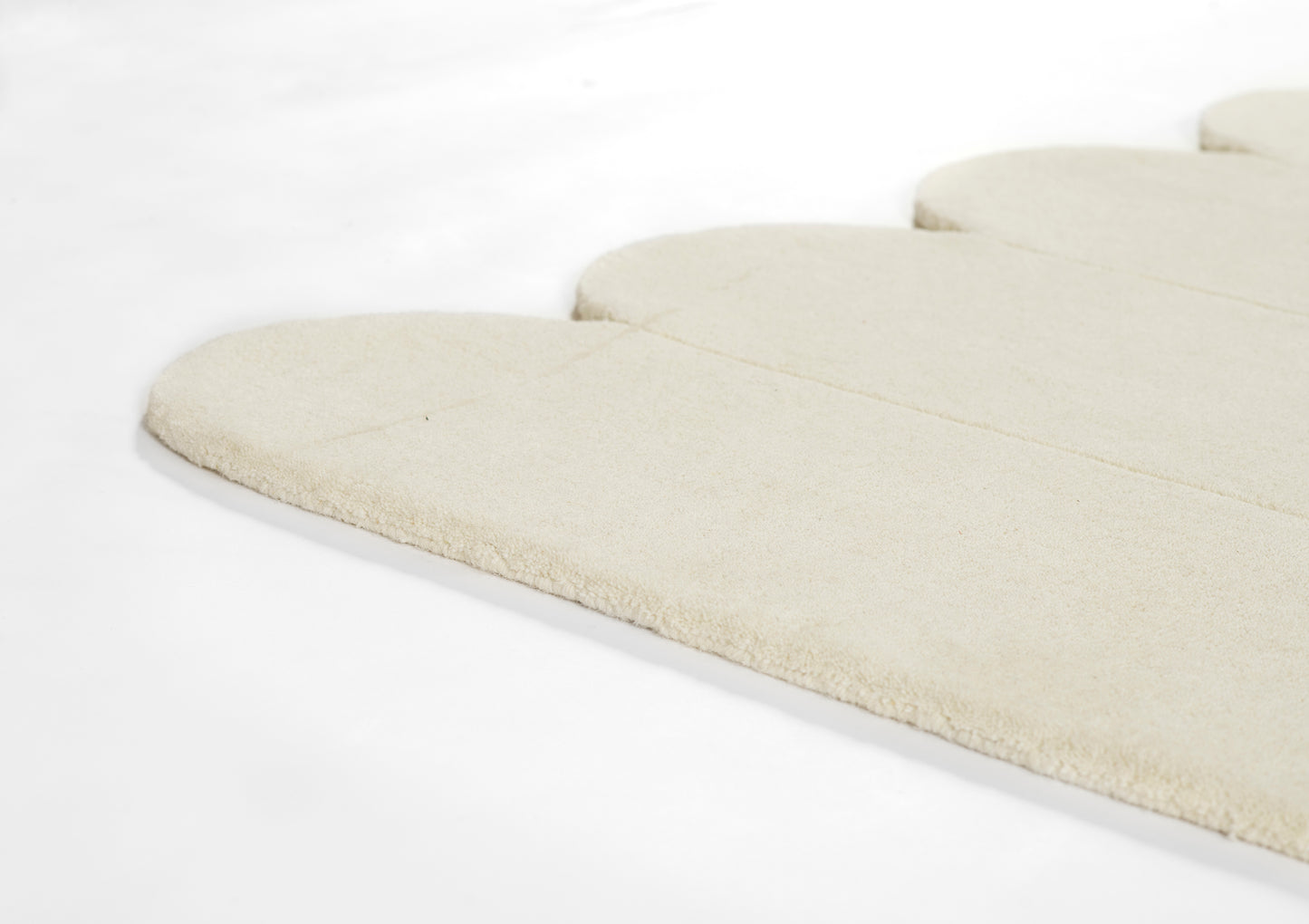 Cream-colored plush fabric with rounded, scalloped segments; soft rug or mat.