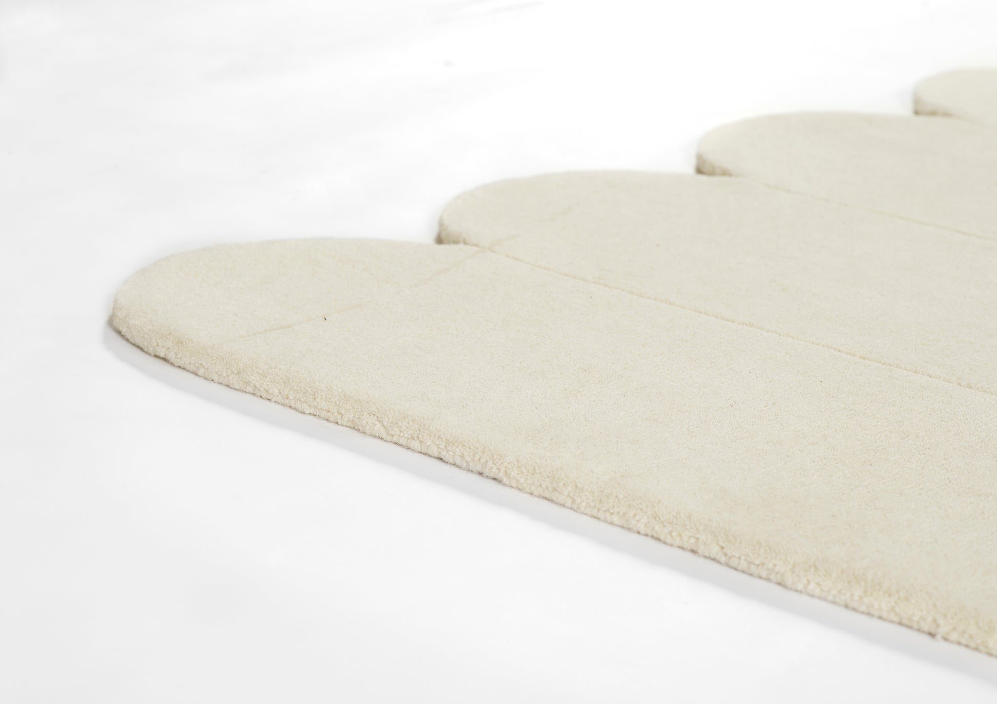 Cream-colored plush fabric with rounded, scalloped segments; soft rug or mat.