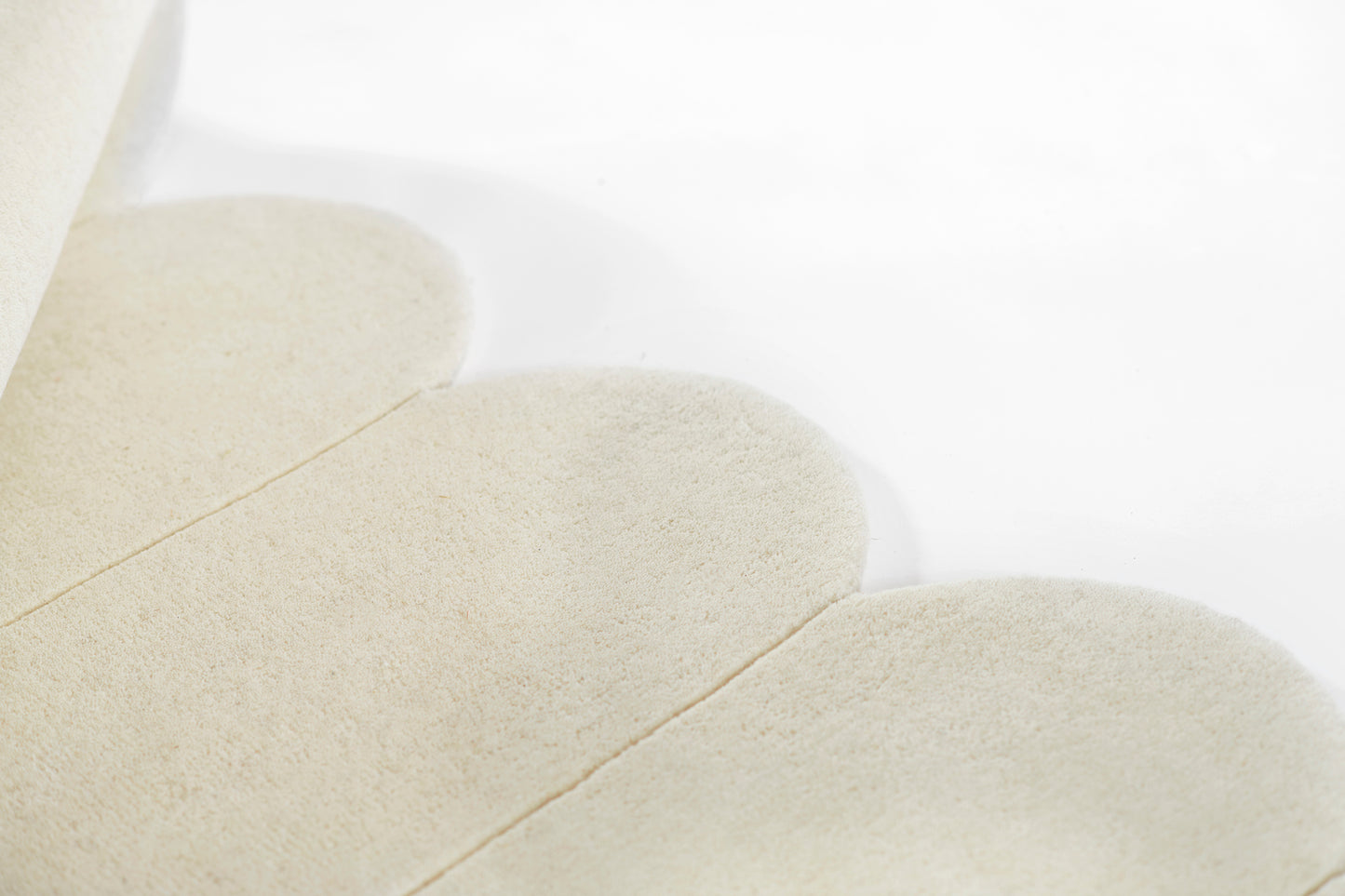 Cream-colored rug; close-up of soft textured pile with rounded oval shapes.