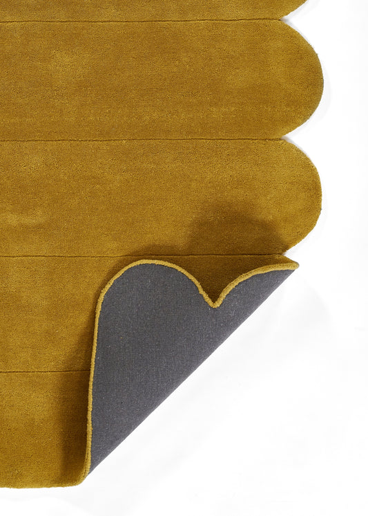 Mustard rug with scalloped edge and stacked stripe design; gray back exposed.