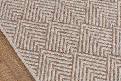 Beige geometric rug with nested chevron squares on wooden floor; textured woven pattern.