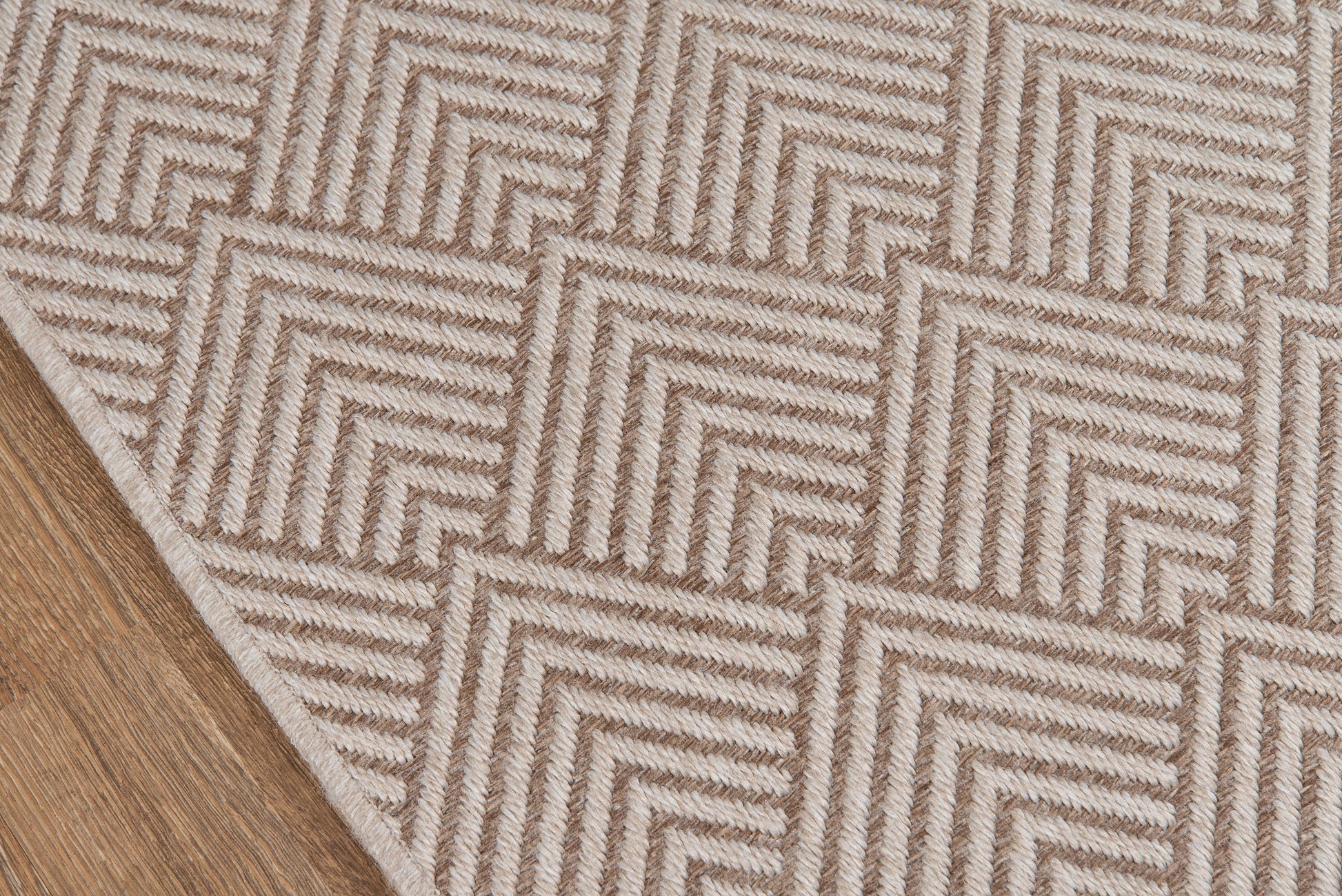 Beige textured area rug with raised chevron zigzag pattern on a wooden floor.