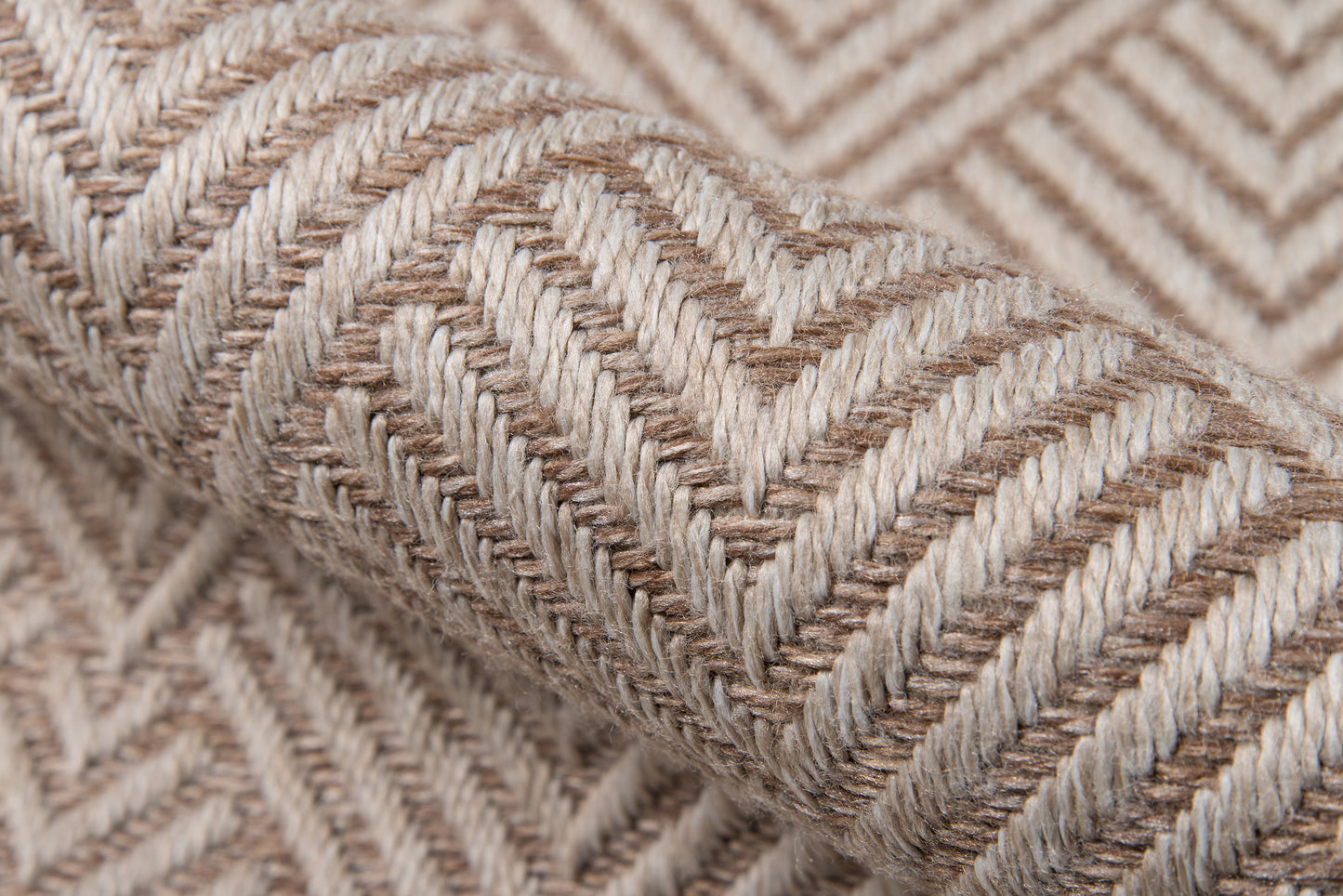Beige chevron woven fabric with thick braided texture, jute-like rug material in a rolled view.