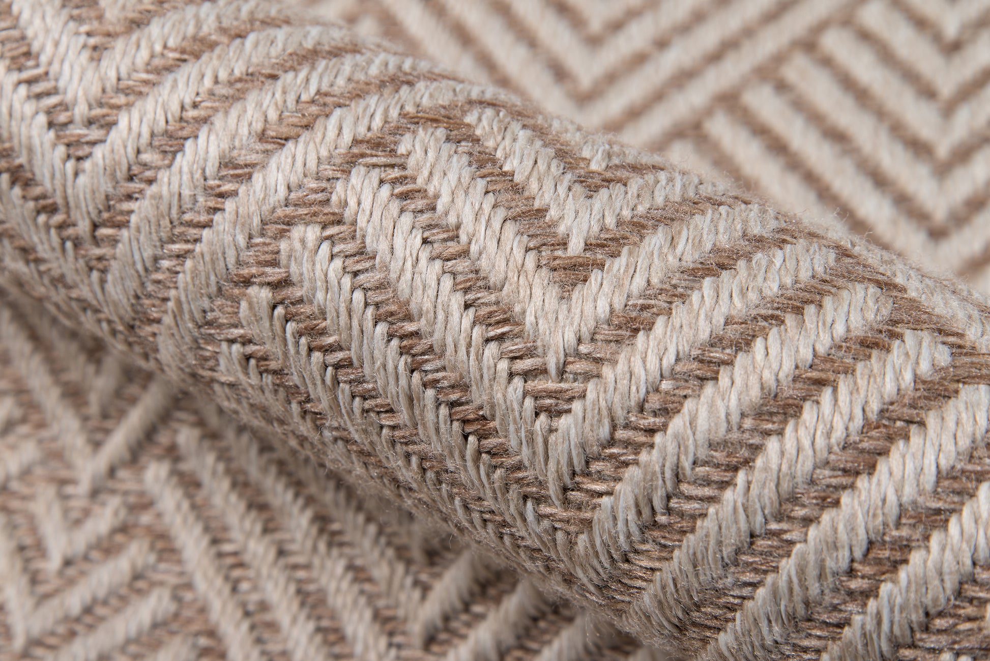 Beige and cream chevron woven rug sample with thick braided fibers, rolled for display.