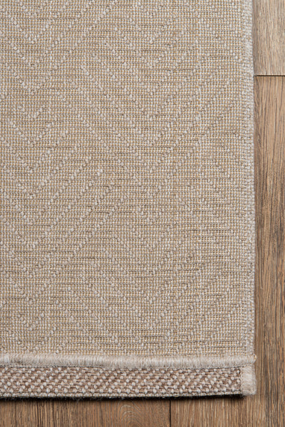 Beige woven area rug with a subtle geometric pattern and textured border on wood flooring.